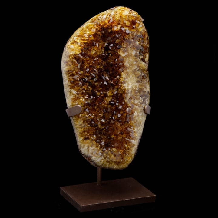 Side view of large golden Citrine crystal cluster on metal stand.